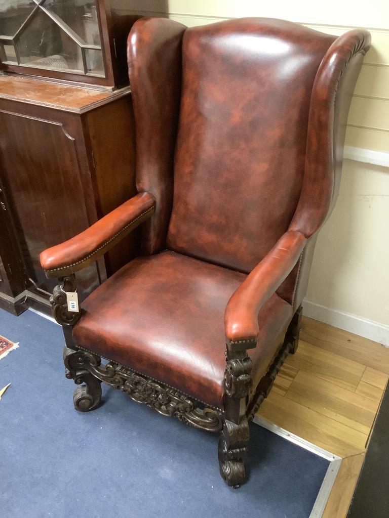 A Carolean style carved walnut and burgundy leather wing armchair, width 72cm, depth 86cm, height 126cm